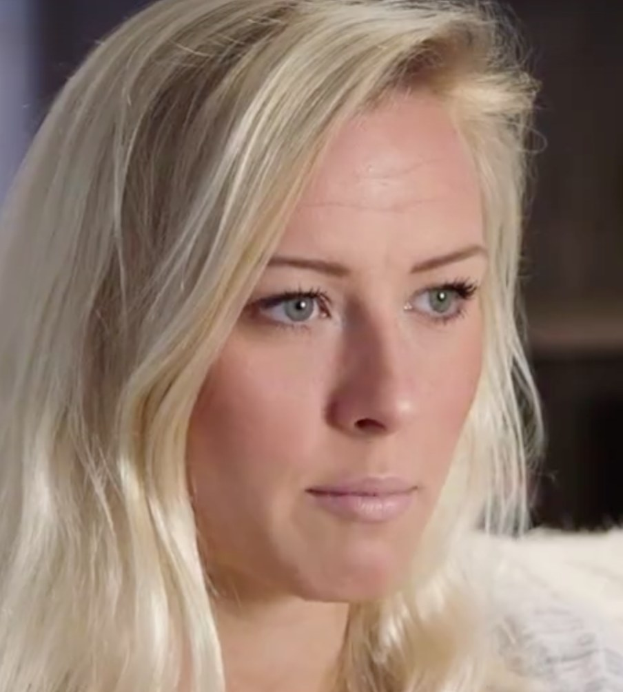 Blonde Frau mit blauen Augen im Vordergrund, unscharfer Hintergrund, sieht besorgt aus.