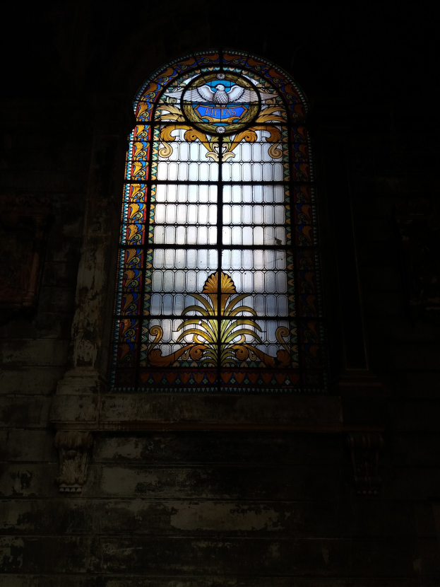 Ein buntes Glasfenster mit detaillierten Mustern in der Mitte eines alten Gebäudes.