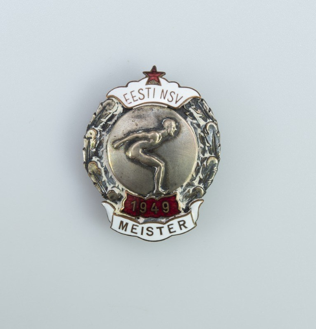 Eine silberne Anstecknadel mit einem roten Stern und Text, Emblem der Olympischen Spiele 1949 in Deutschland.
