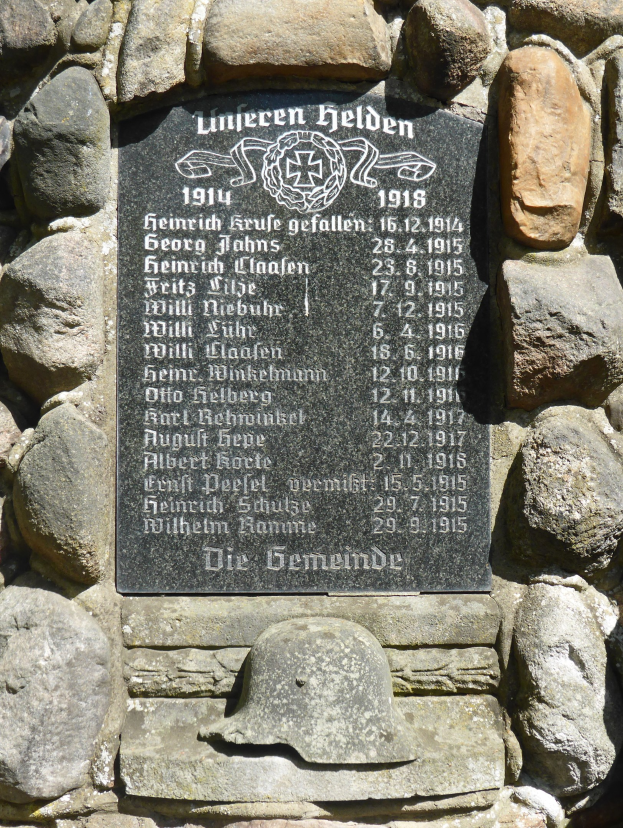 Steinmauer mit Gedenktafel und Helm darauf, mit Inschrift.