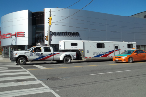 Ein Polizeilaster ist vor einem Gebäude mit Text darauf geparkt, mit einer Ampel mit Stange und Drähten im Vordergrund und Bäumen und einem klaren blauen Himmel im Hintergrund.