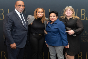 Vier Personen auf einem roten Teppich bei der "Liberty Justice for All Awards"-Veranstaltung, die für ein Foto posieren.