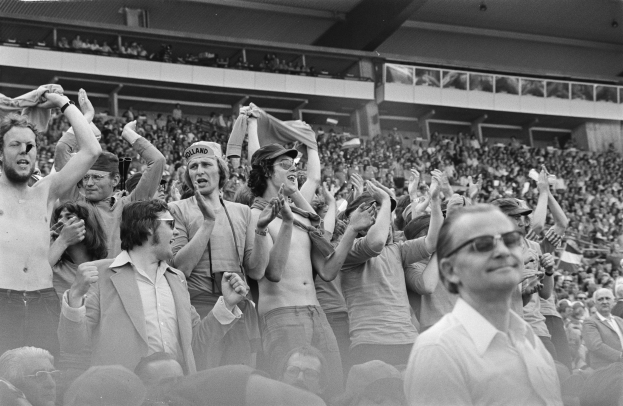 Schwarzes und weißes Foto einer Menge in einem Stadion, einige tragen Brillen.