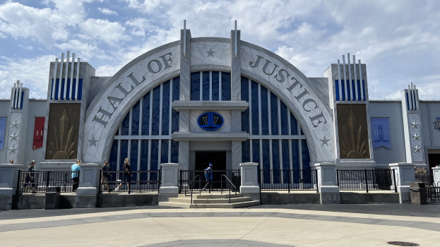 Der Eingang zum Hall of Justice im Disney's Hollywood Studios, mit Menschen davor, an einem bewölkten Himmel.