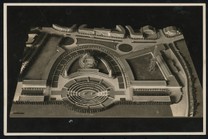 Schwarzes und weißes Rahmenfoto eines detaillierten Modellkonzertsaals mit einer großen zentralen Kuppel, Steinwänden, Metalldach und einer hell erleuchteten Bühne, die von einer Menge umgeben ist.