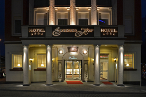 Das Essenerhof Hotel in Berlin, Deutschland, ein mehrstöckiges Gebäude mit Fenstern, Türen, Säulen, Lampen und einem Namensschild, sowie einer Straße mit Fahrzeugen auf der rechten Seite, unter einem klaren Himmel.