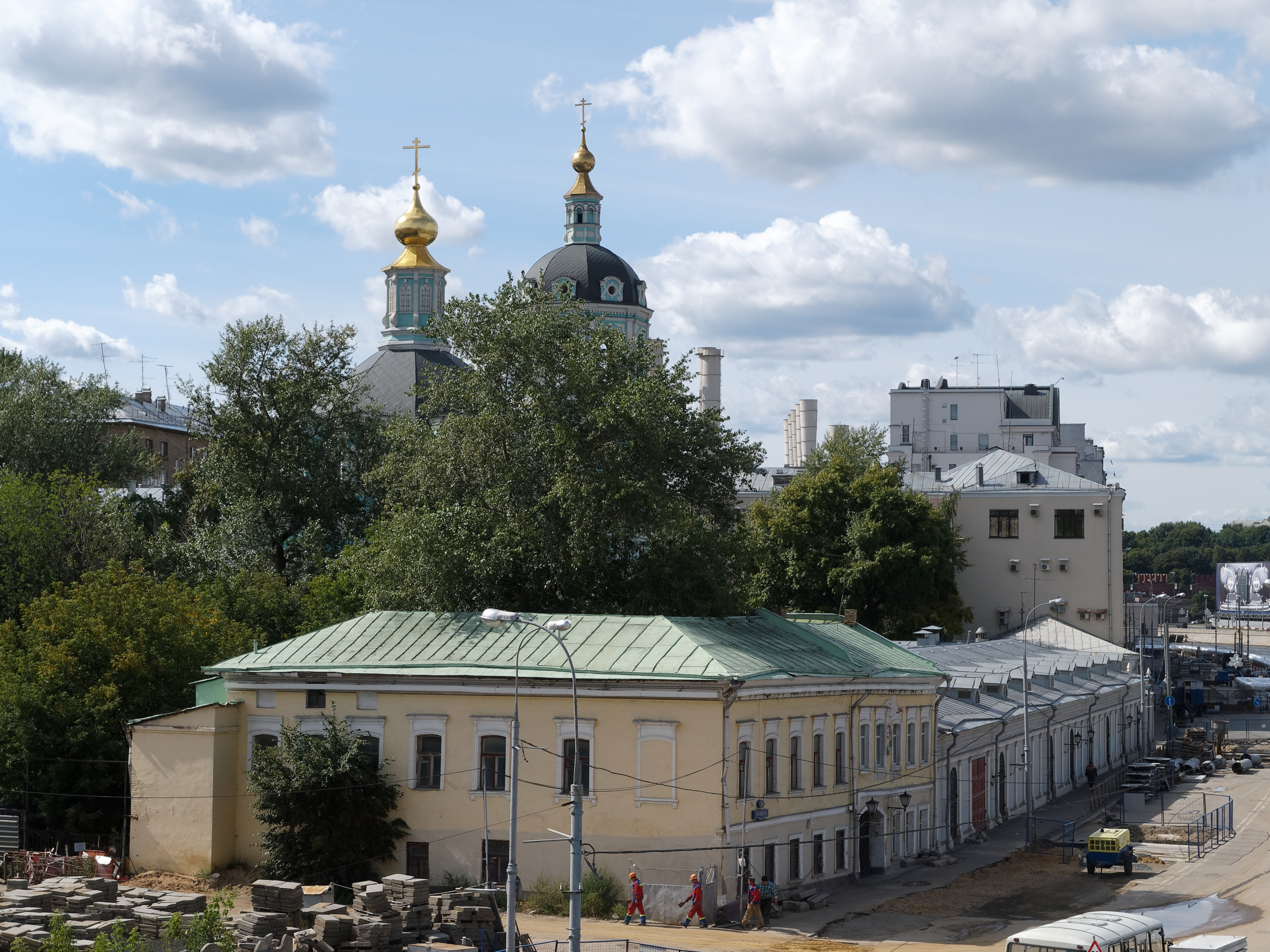 Eine Stadtansicht mit der Kirche der Versöhnung am Nerl im Hintergrund und umgeben von Gebäuden, Bäumen, Straßeninfrastruktur, Fahrzeugen, Fußgängern und einer bewölkten Himmel.