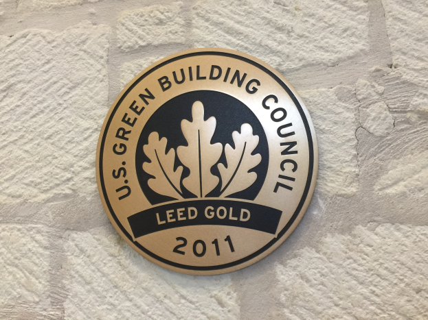 Logo der U.S. Green Building Council an einer Gebäudefassade, das einen grünen Schild mit weißer Umrandung, schwarzen Text 'Green Building Council' und einen Lorbeerkranz zeigt.