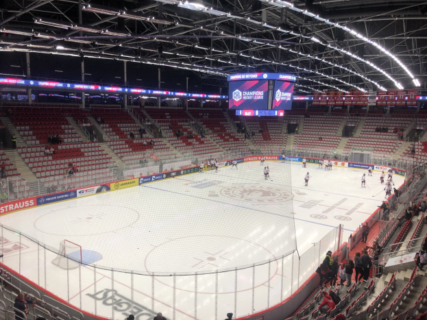 Eishockeyspiel in einer großen Arena zwischen den St. Louis Blues und Detroit Red Wings, mit Zuschauern auf den Sitzen und Stehplätzen in der Nähe der Eisfläche umgeben von einem Zaun und Anzeigebildschirm.