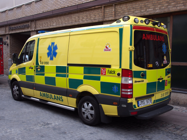 Ambulanz vor einem Backsteingebäude mit Text geparkt, mit einem Feuerlöscher auf der linken Seite sichtbar.