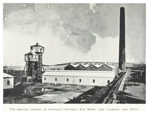Schwarzes und weißes Foto einer Industrieanlage mit mehreren Gebäuden, einem hohen Turm und Rauch, der aus einem Schornstein austritt, mit Text unten.
