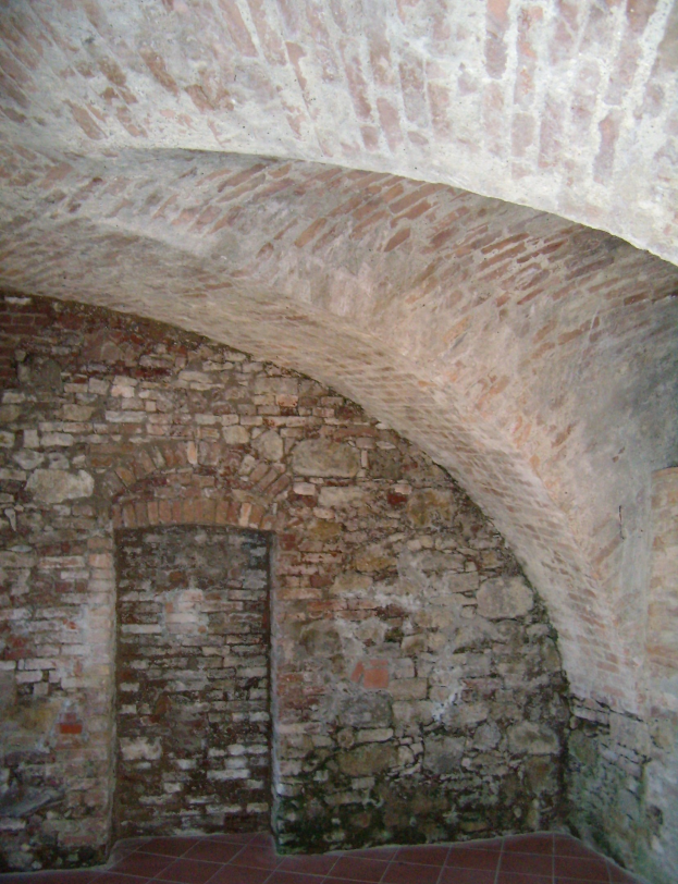 Altes Backsteingebäude mit gewölbter Decke und gefliestem Boden, das von gebogenen Backsteinwänden geprägt ist.