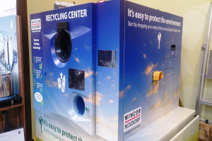 Blaues Recyclingzentrum mit einem "Recyclingzentrum"-Schild in der Mitte, einem Gestell mit Gegenständen links, einem einzelnen Gegenstand auf dem Boden rechts und Hintergrundbeleuchtung an einer Wand.