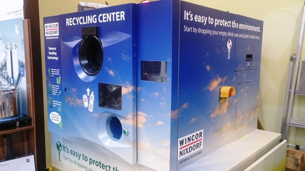 Blaues Recyclingzentrum mit einem "Recyclingzentrum"-Schild in der Mitte, einem Gestell mit Gegenständen links, einem einzelnen Gegenstand auf dem Boden rechts und Hintergrundbeleuchtung an einer Wand.