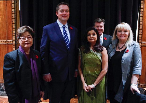 Gruppe von Menschen vor einem schwarzen Vorhang mit einer hölzernen Wand dahinter, die scheinbar Liberale bei einer Versammlung sind.