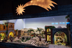 Eine Krippe-Ausstellung im Museum, mit Menschen, Tieren, Häusern, Bäumen und anderen Gegenständen, beleuchtet von oben.