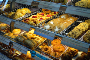 Ein Bäckereischaufenster voller verschiedener Kuchen und Kekse, mit Schildern, die die Art der Backwaren angeben.