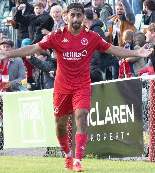 Ein Fußballspieler in roter Uniform rennt mit ausgebreiteten Armen auf einem Feld, umgeben von einer Menge, mit einem "Middlesbrough FC v Swansea City - Sky Bet Championship"-Schild im Hintergrund.
